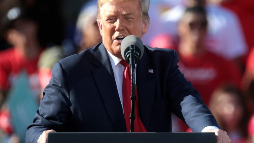 Donald Trump speaking into a microphone at a campaign rally