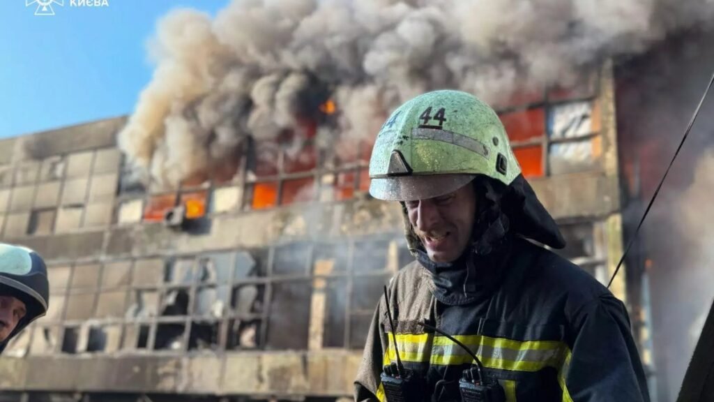 Ukrainian firefighter in front of a burning building in Kyiv after a Russian attack